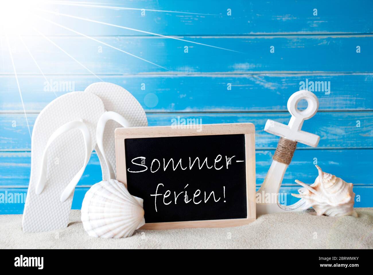 Chalkboard With German Text Sommerferien Means Summer Holidays. Blue Wooden Background. Sunny Summer Card With Holiday Greetings. Beach Vacation Symbo Stock Photo