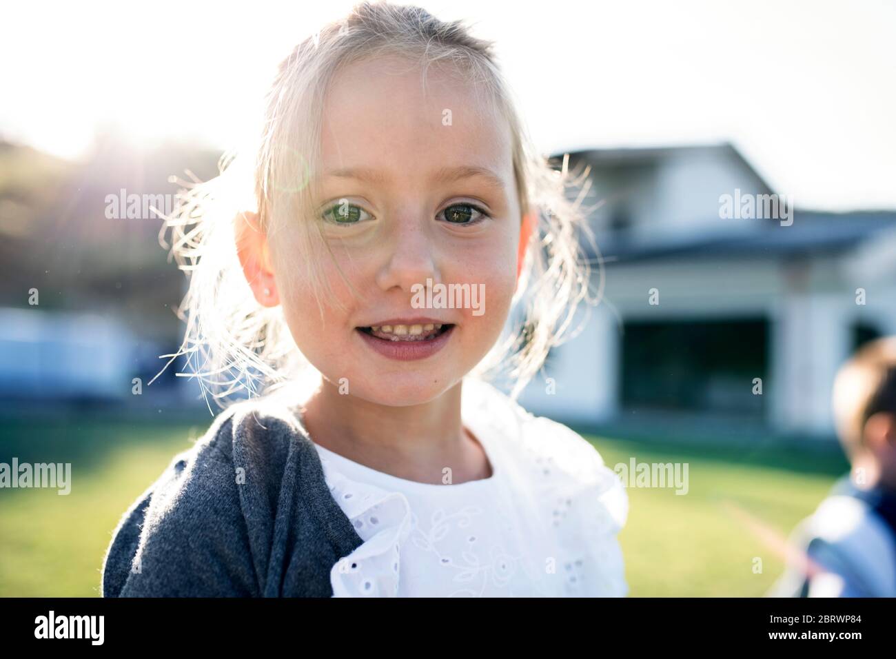 Front view of small girl standing outdoors, looking at camera. Stock Photo