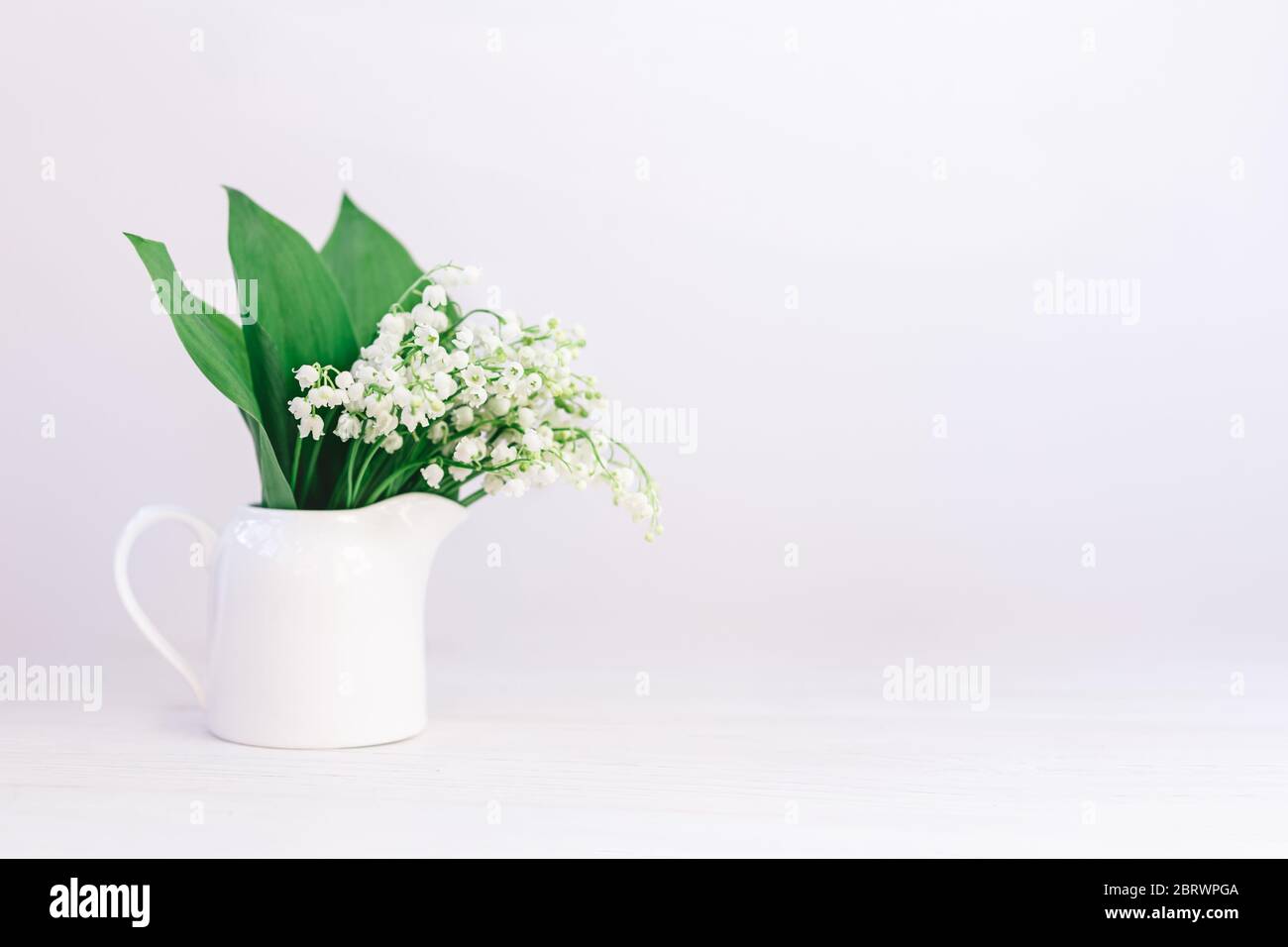 Romantic bouquet of the lilies of the valley in a jar on a white ...