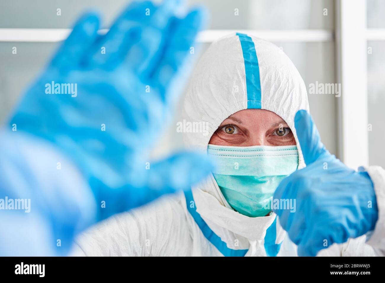 Nurses in protective clothing in clinic hold thumbs up during coronavirus pandemic Stock Photo