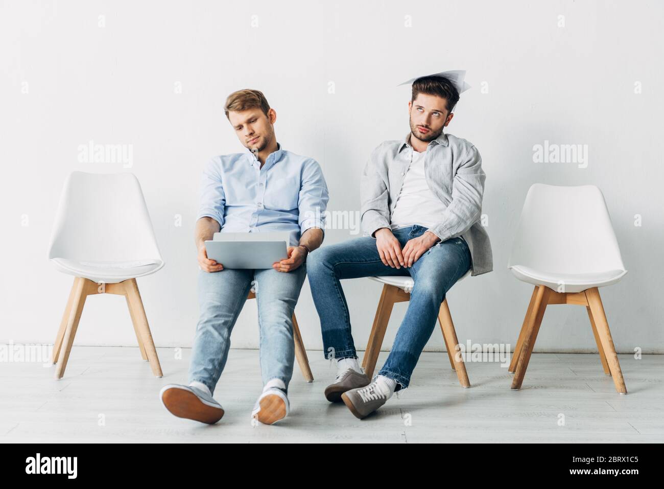 Exhausted candidates with laptop and resume waiting for job interview in office Stock Photo