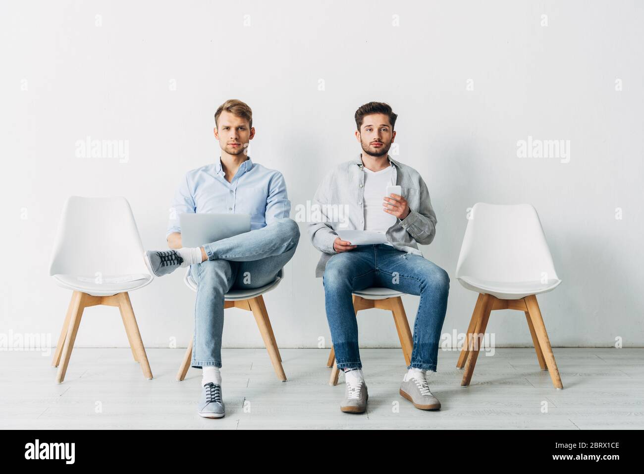 Employees with gadgets and resume looking at camera while waiting for job interview Stock Photo