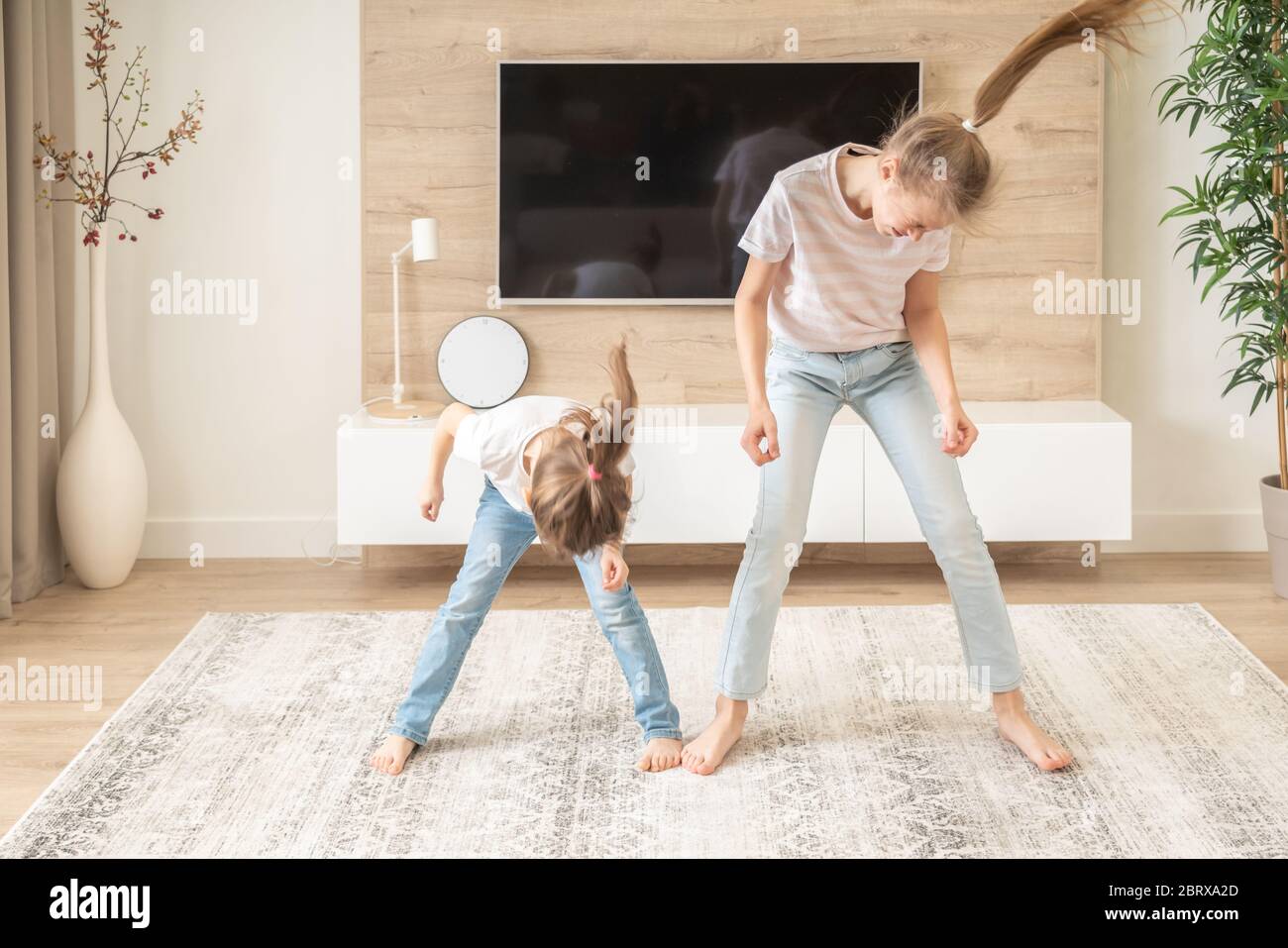 Two sisters having fun dancing in living room, happy family concept