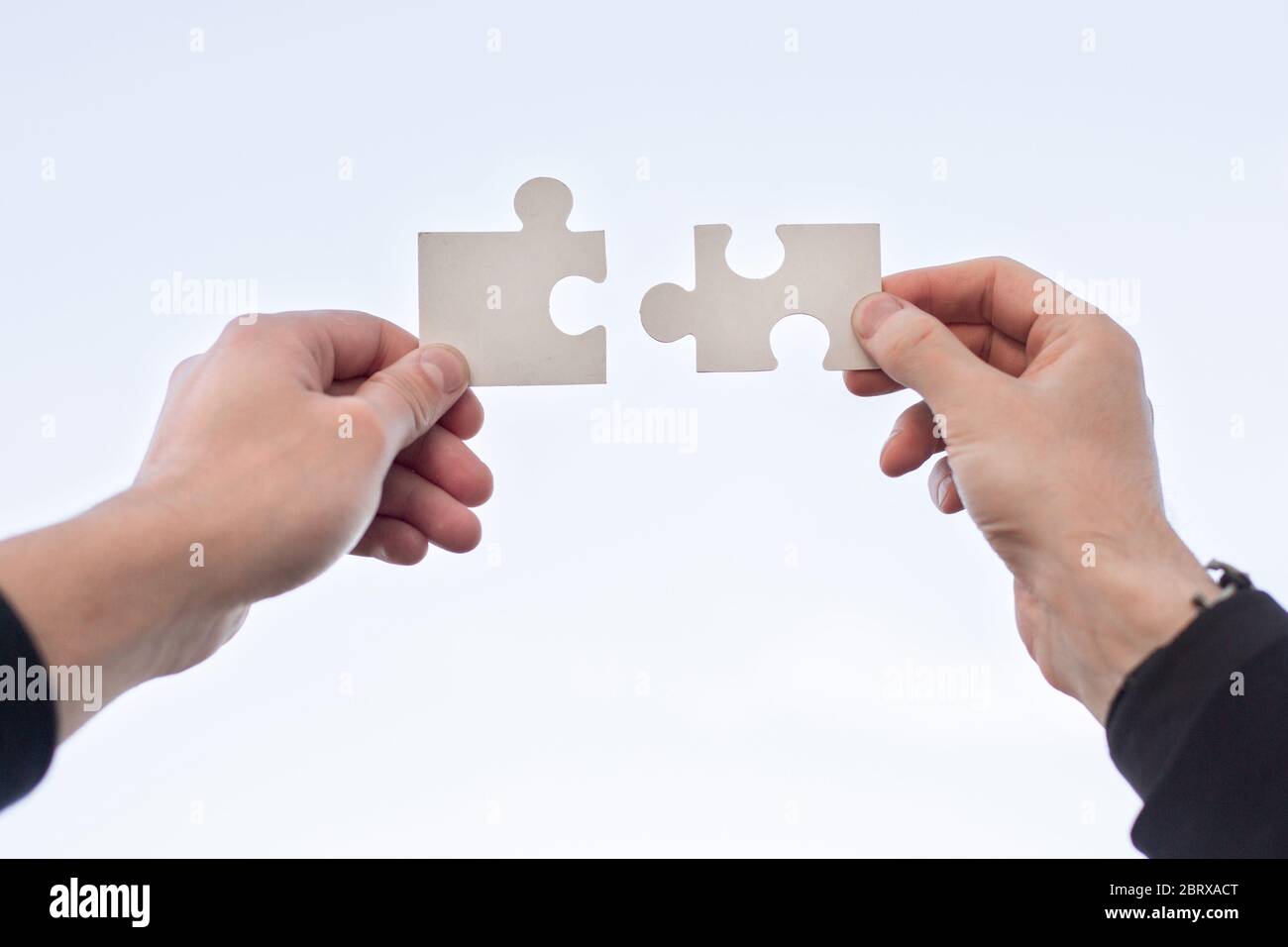 two 2 hands trying to connect couple puzzle piece Stock Photo - Alamy