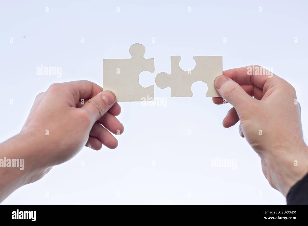 two 2 hands trying to connect couple puzzle piece Stock Photo - Alamy