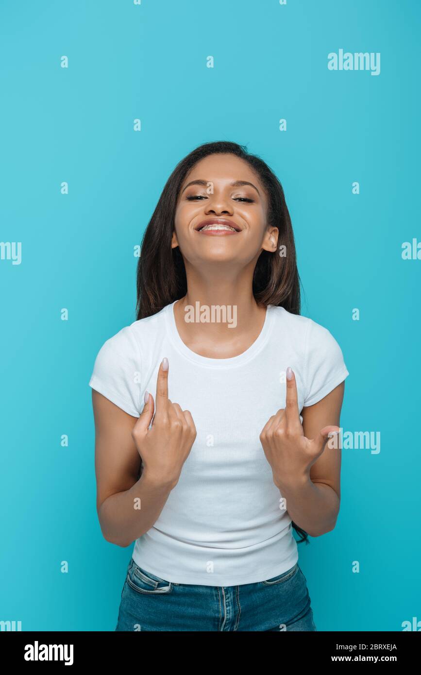 Smiling African American Girl Pointing At Dental Braces On Her Teeth Isolated On Blue Stock