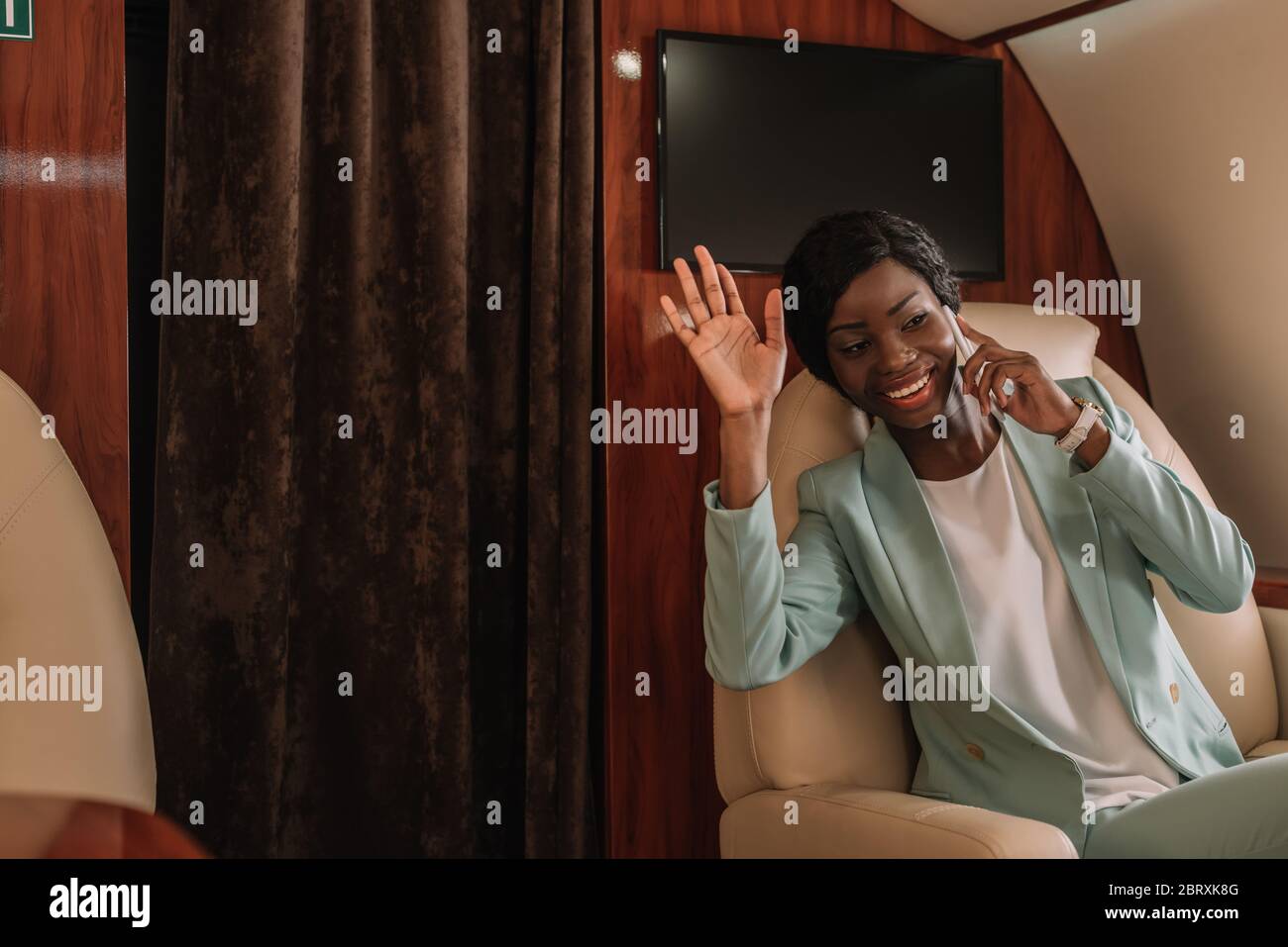happy african american businesswoman waving hand while talking on ...