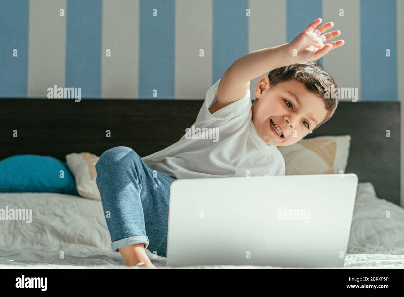 selective focus of happy toddler boy waving hand while having video ...