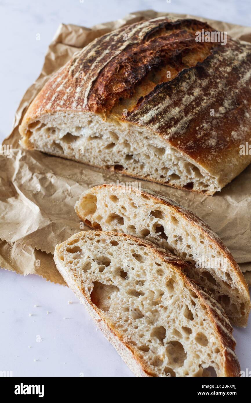 Fresh sourdough loaf and slices from the bakery on a crumpled brown ...
