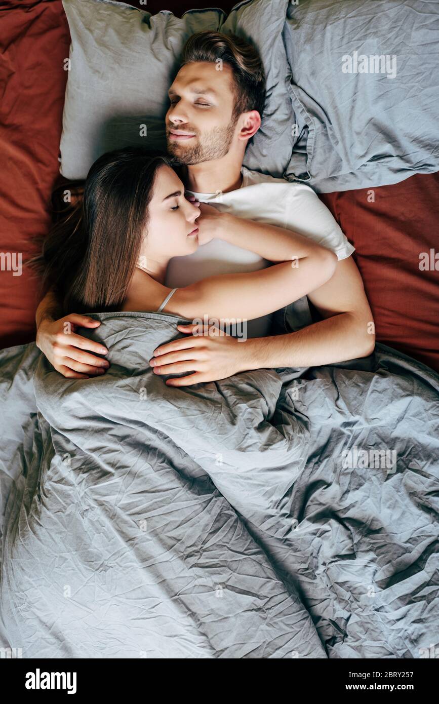 top view of girlfriend and boyfriend hugging while sleeping in bed ...