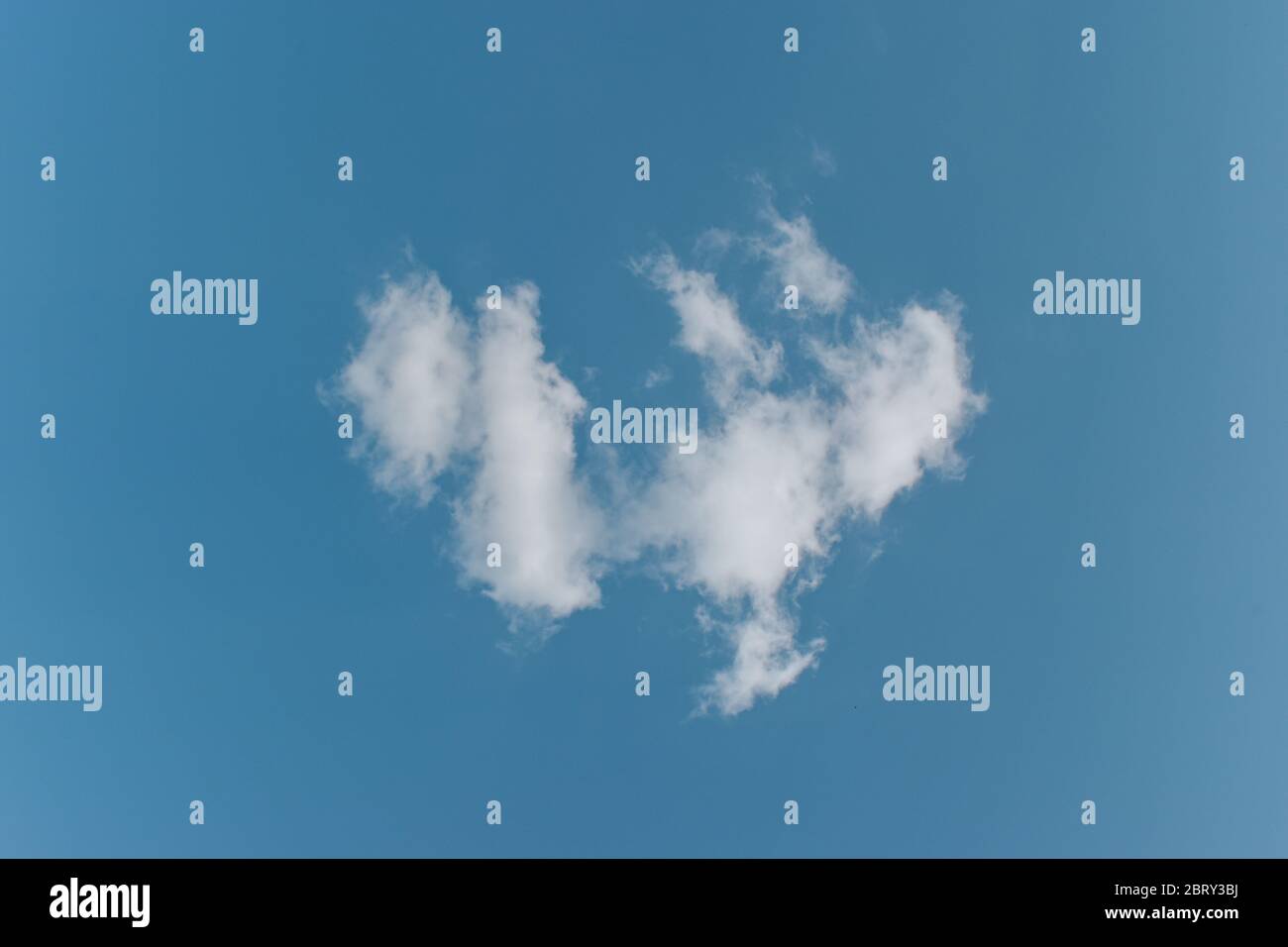Single white cloud on blue sky background. Stock Photo