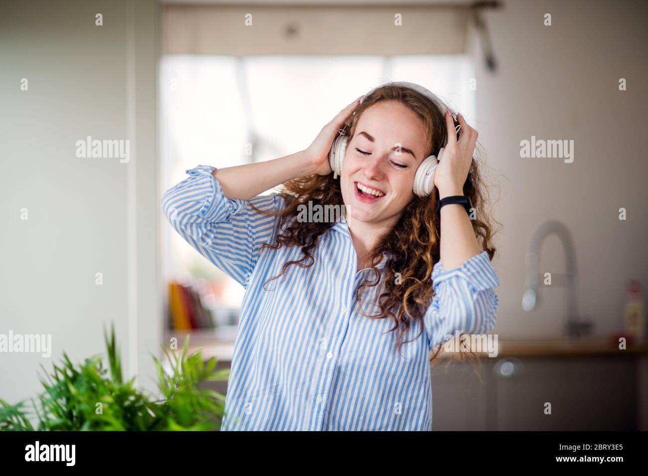 Young woman with headphones relaxing indoors at home. Stock Photo