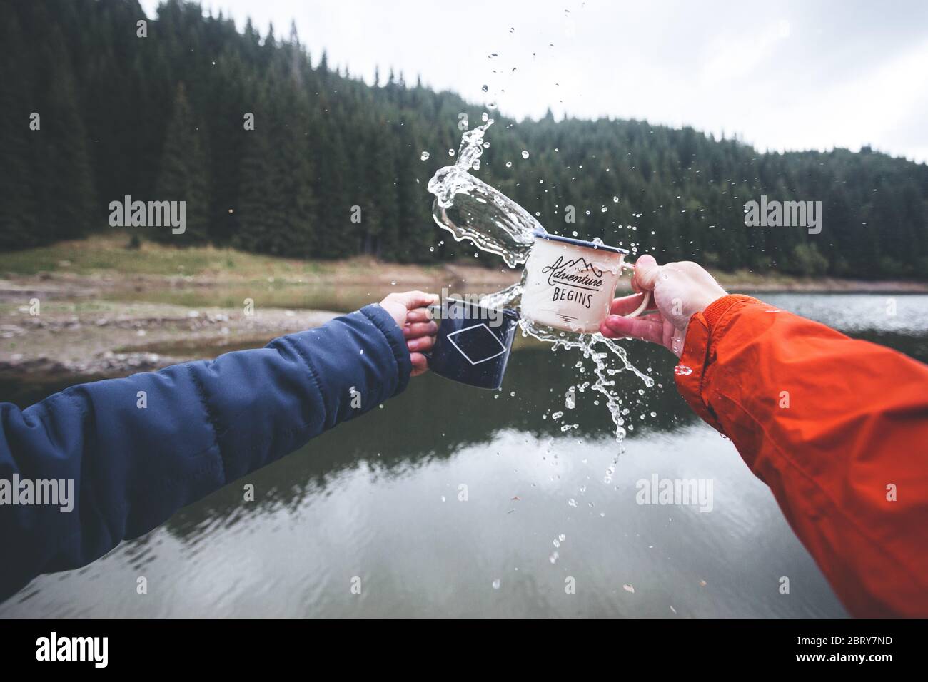 Close up human hands splashing mugs with water by the lake Stock Photo