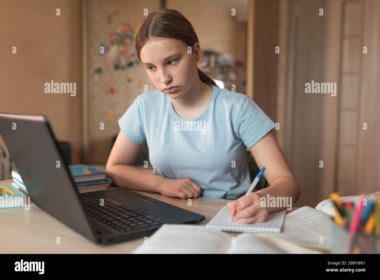 Teen girl writes lessons test tasks in a notebook, electronic education