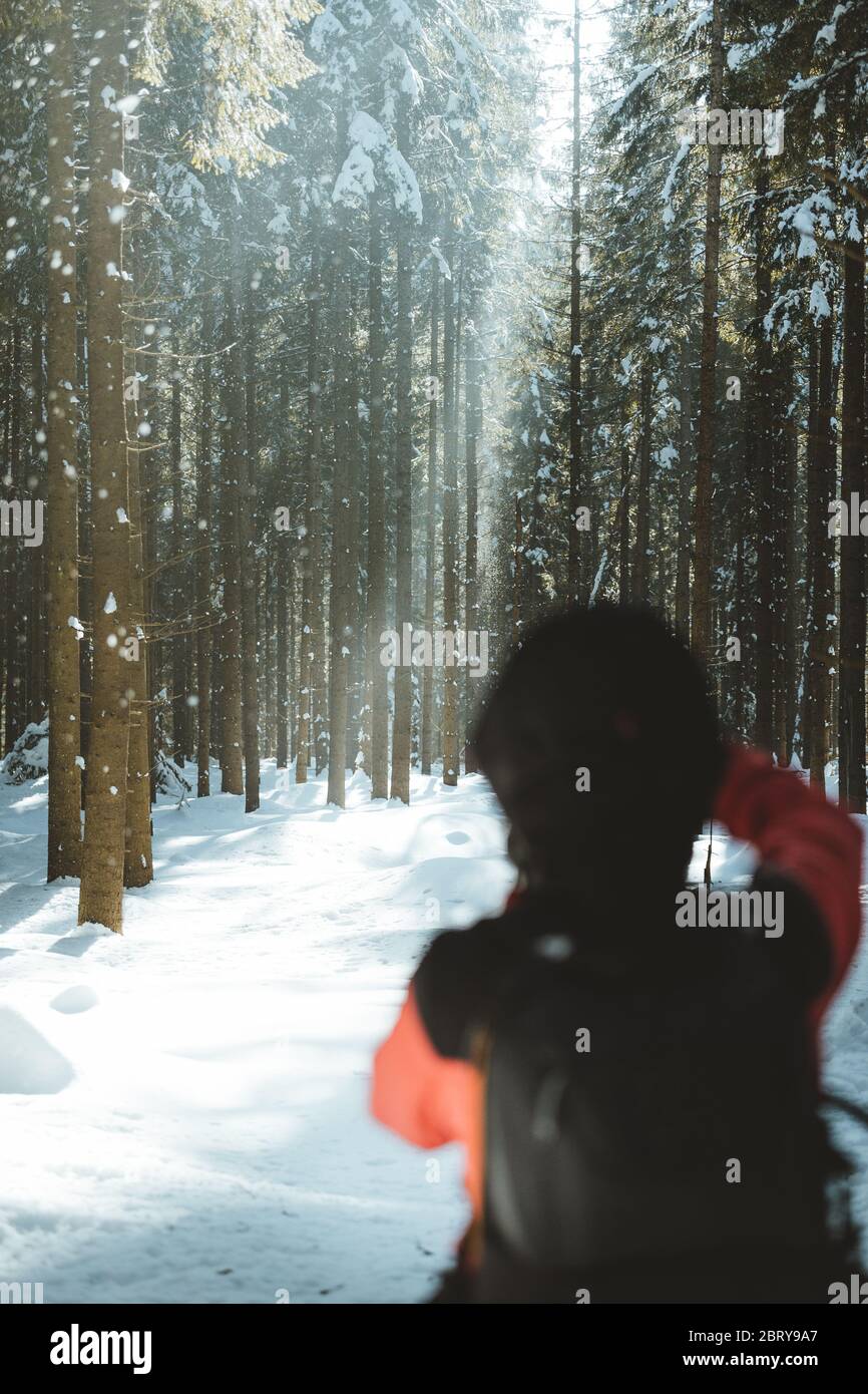 Close up view of a hiker photographing forest landscape with beautiful path of light around. Sunny and snowy winter background Stock Photo