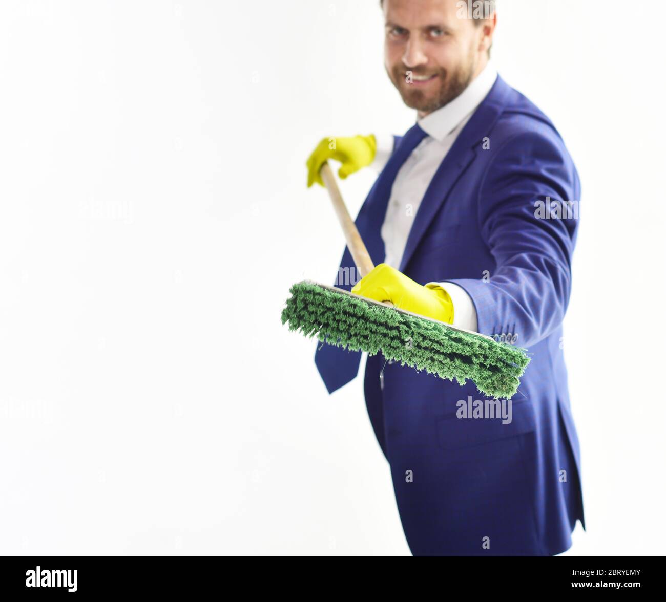 Bearded man in formal suit with tie, smilling face and sweep. Happy  businessman with mop. Boss or director holds cleaning supplies and smiles.  Cleaning service, laundering, fraud, financial concept Stock Photo -
