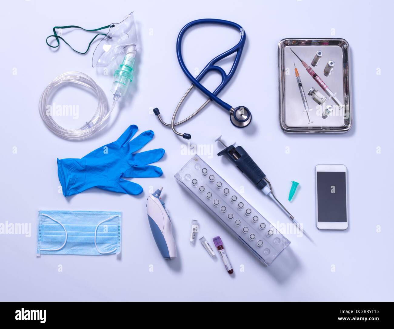 Potential way out of lockdown stage. Medical equipment on a grey background, oxygen mask, stethoscope, mobile phone with a contact tracing app, syringes for vaccine, blue gloves and digital thermometer. Stock Photo