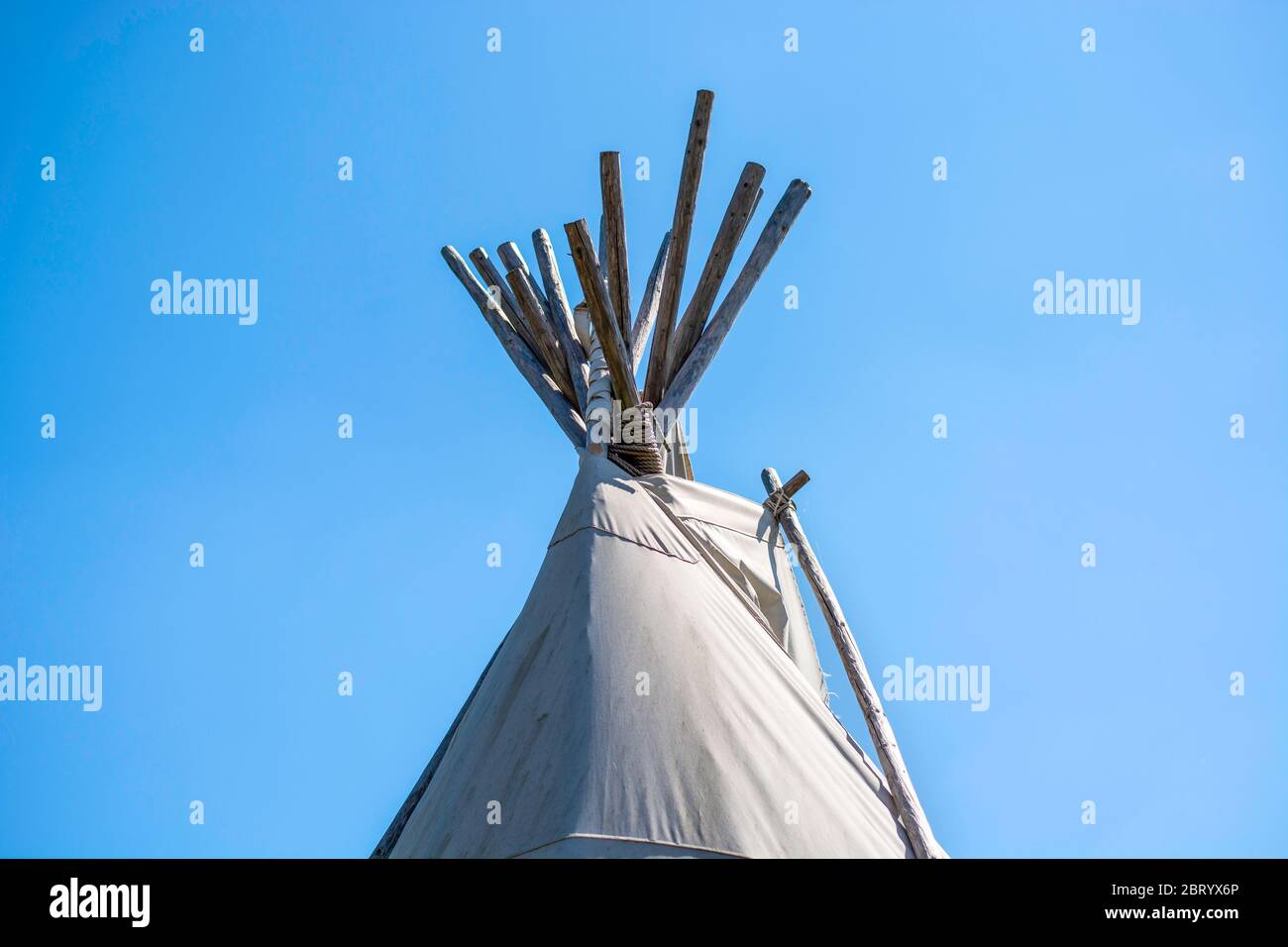 Top of Native American wigwam tent lodge or teepee tent against clear blue sky background. Stock Photo