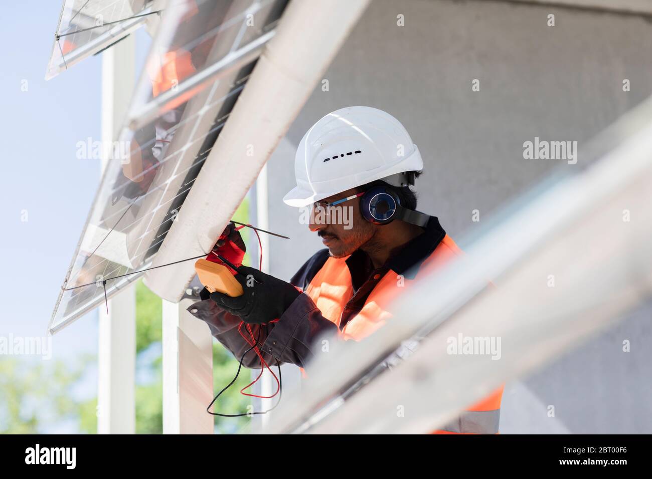 Male engineer wearing hardhat and ear protectors working on construction site. Stock Photo