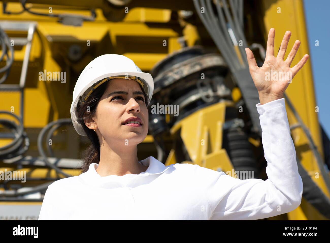 Female architect wearing white hard hat working on construction site. Stock Photo