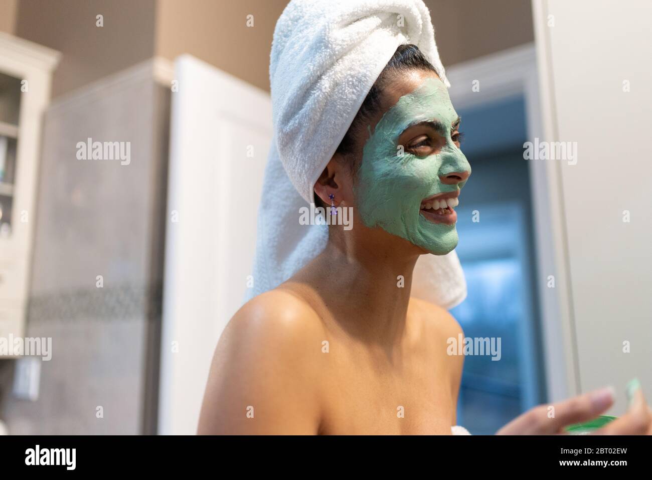 Woman standing in bathroom, applying face mask after bath. Stock Photo