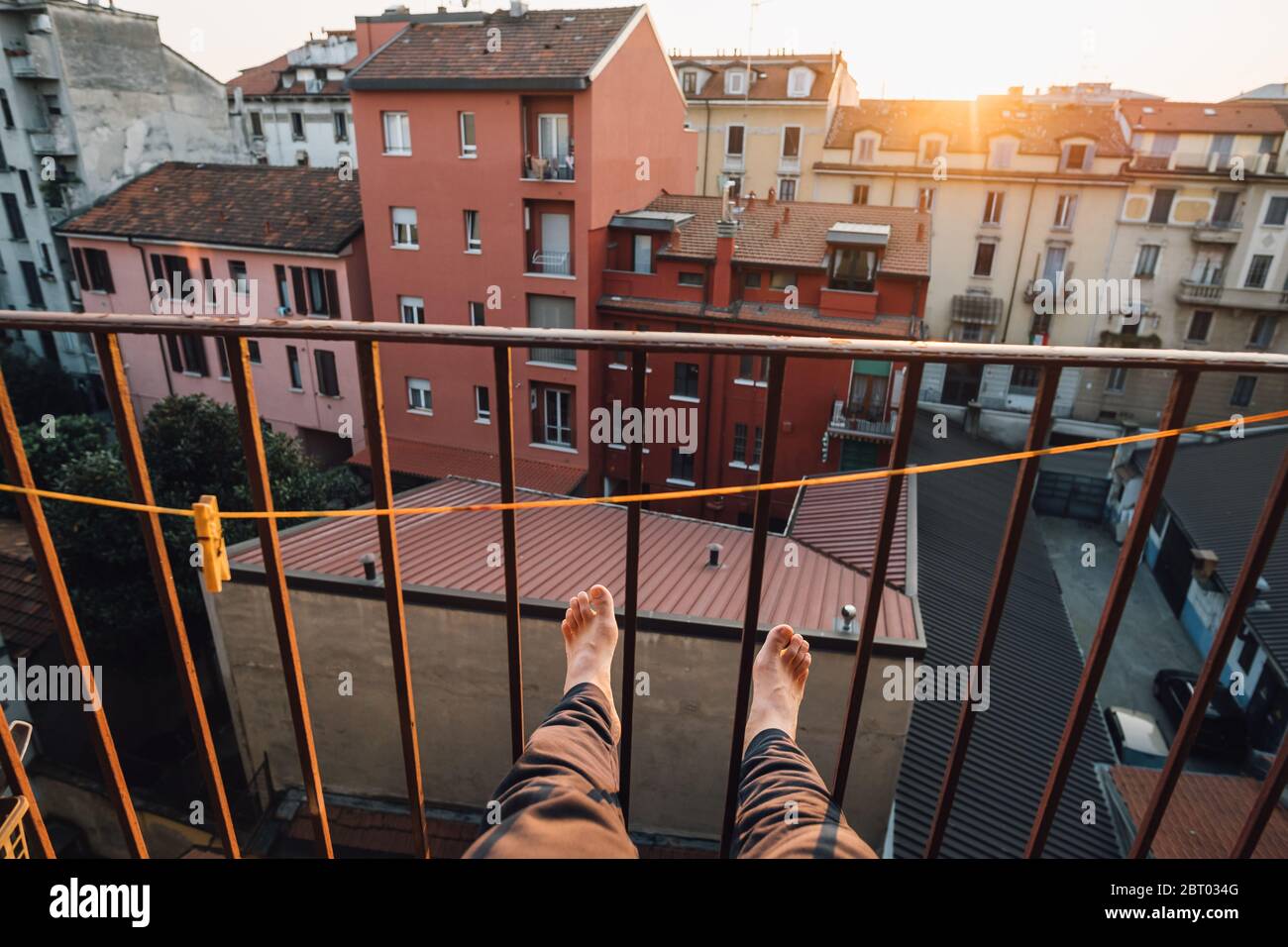 Barefoot man sitting on balcony in Milan, Italy while self isolating during Corona crisis. Stock Photo