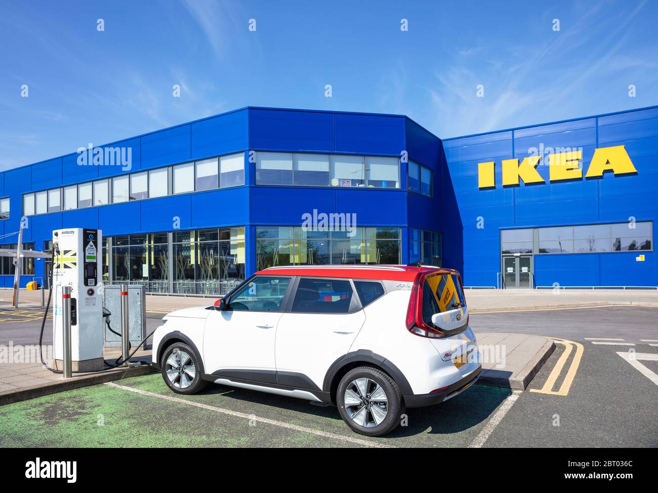 Large yellow IKEA store sign on the side of blue IKEA warehouse with an electric car charging Nottingham East Midlands England UK GB Europe Stock Photo