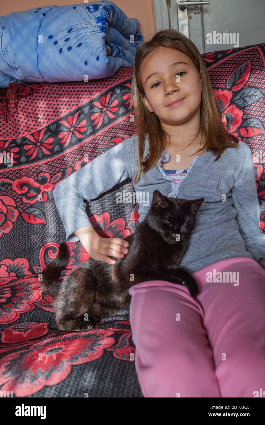 Little girls playing with black cat in the rural home. Stock Photo