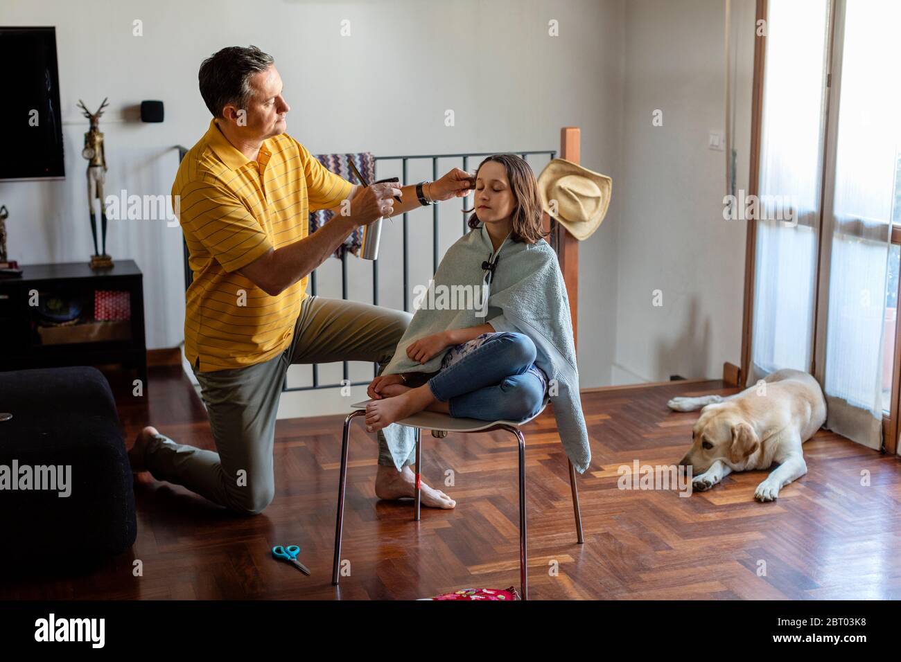 Father cutting his daughter's hair at home, during the stay at home lockdown period. Stock Photo