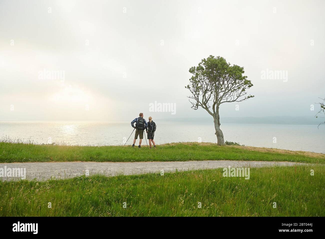 A mature couple of hikers looking out over the sea on a coastal path. Stock Photo