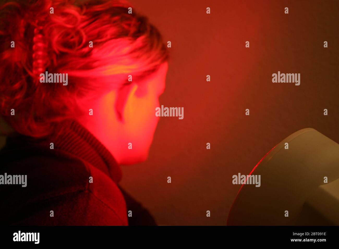 young woman is illuminated by red light Stock Photo