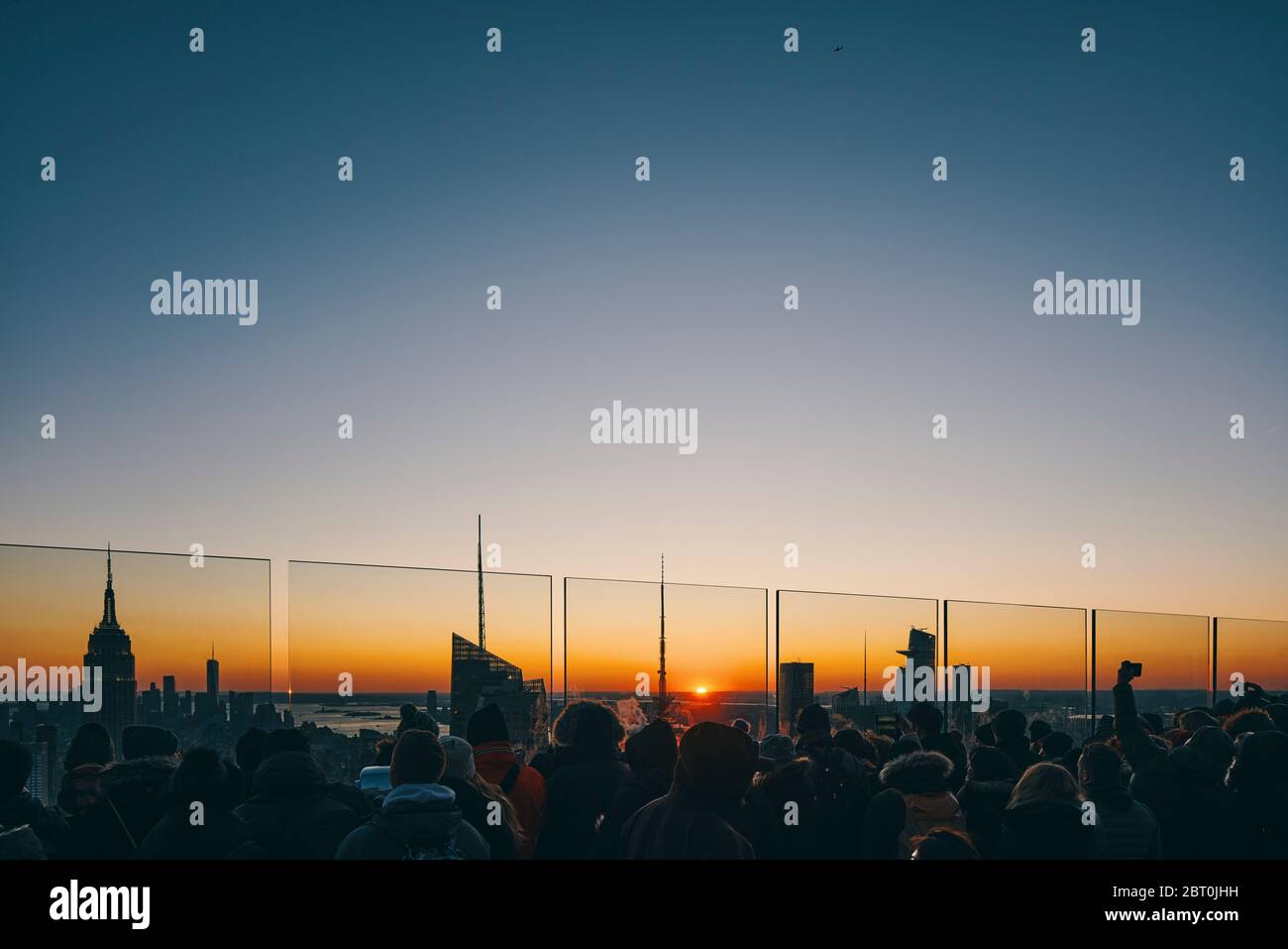View of Manhattan skyline with illuminated skyscrapers at sunset, New York City Stock Photo