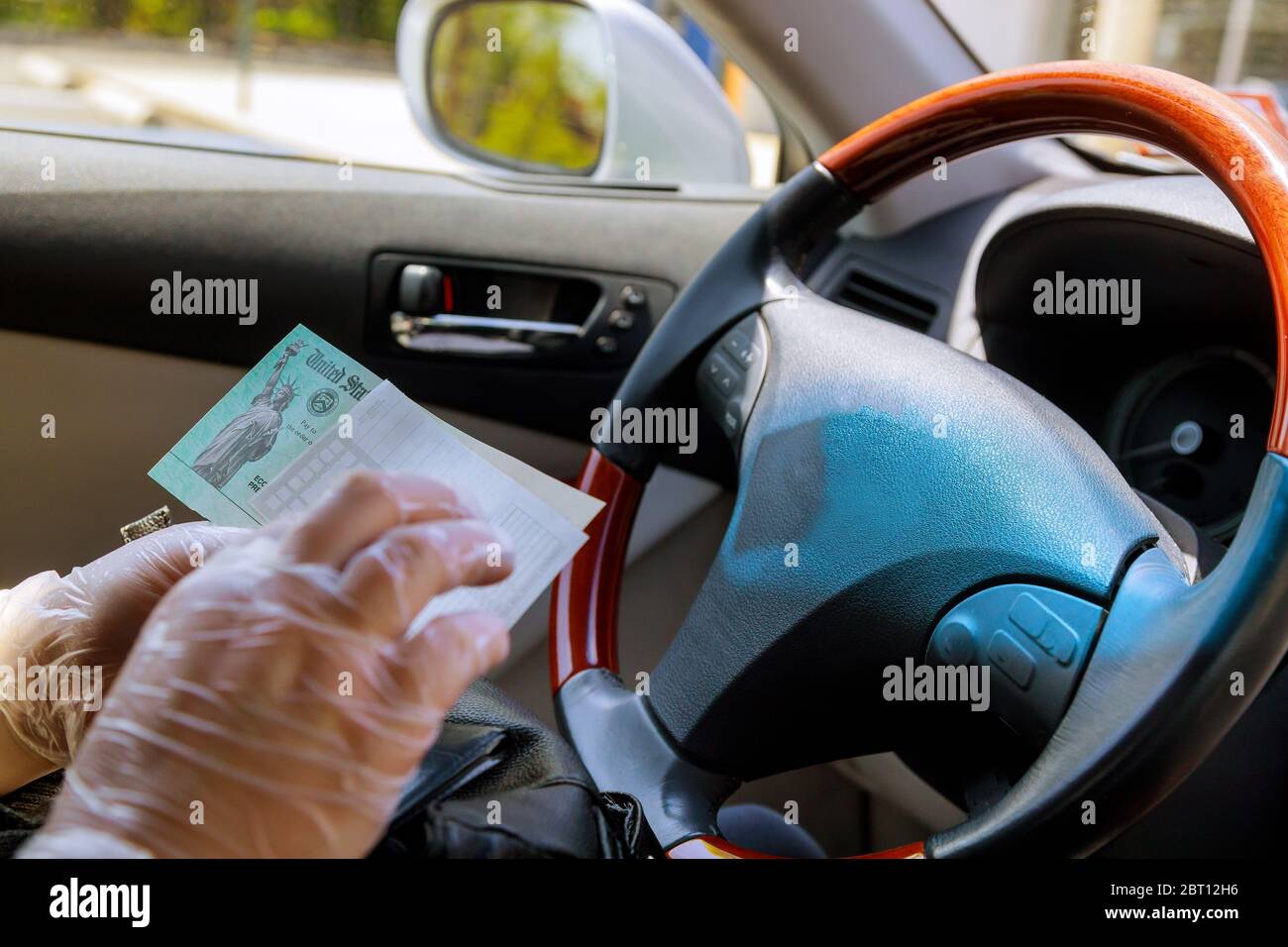 Writing a paper slip depositing government stimulus check with gloves on for safety in car Stock Photo