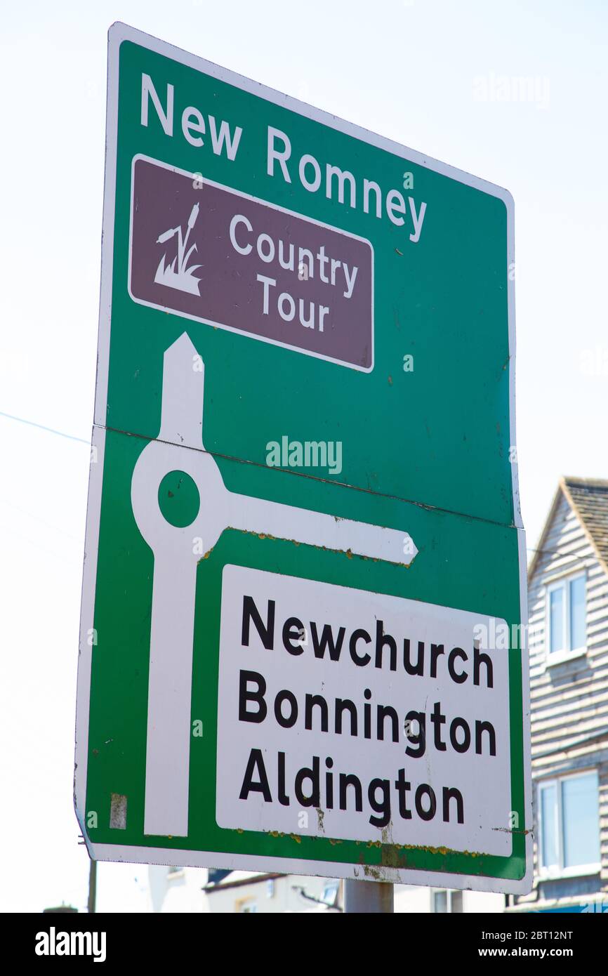 A road sign showing a roundabout with directions to New Romney Country Tour, Newchurch, Bonnington and Aldington. Stock Photo