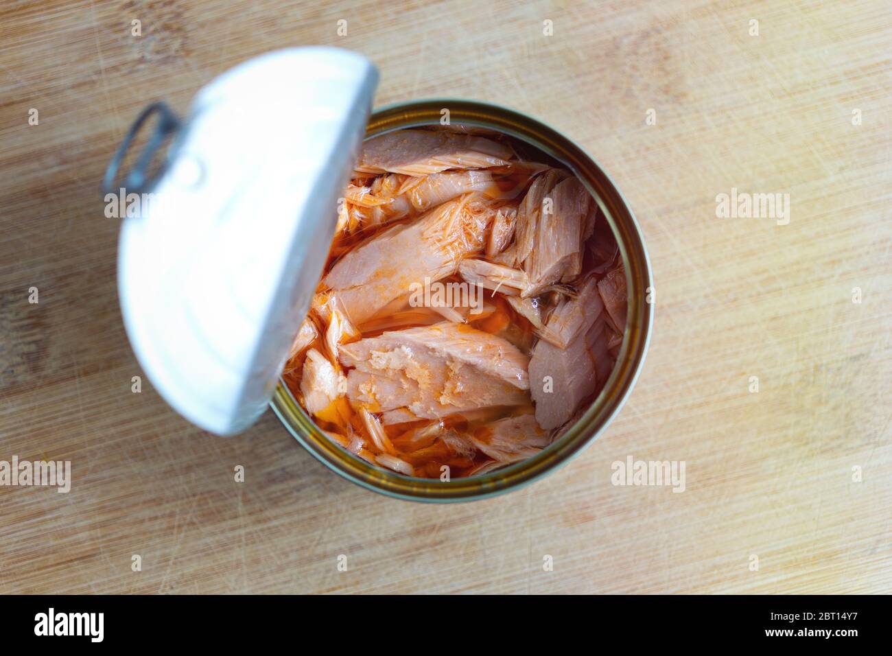 Close up of open canned tuna in red oil on wooden table, top view Stock Photo