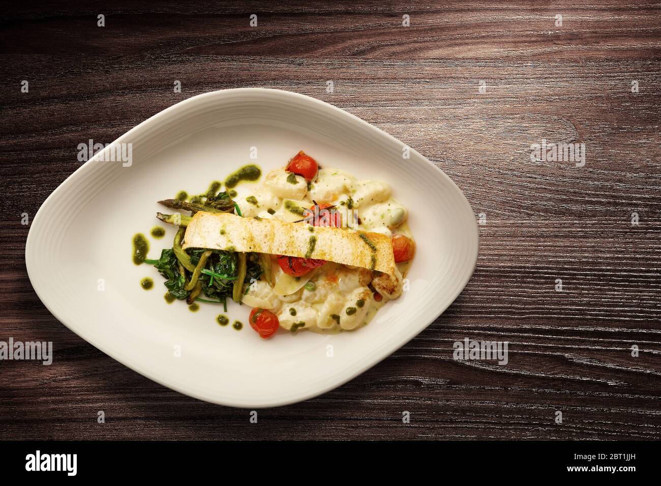 Directly above shot of a stylish Nouvelle Cuisine plate of pasta with asparagus and spinach over wooden background Stock Photo