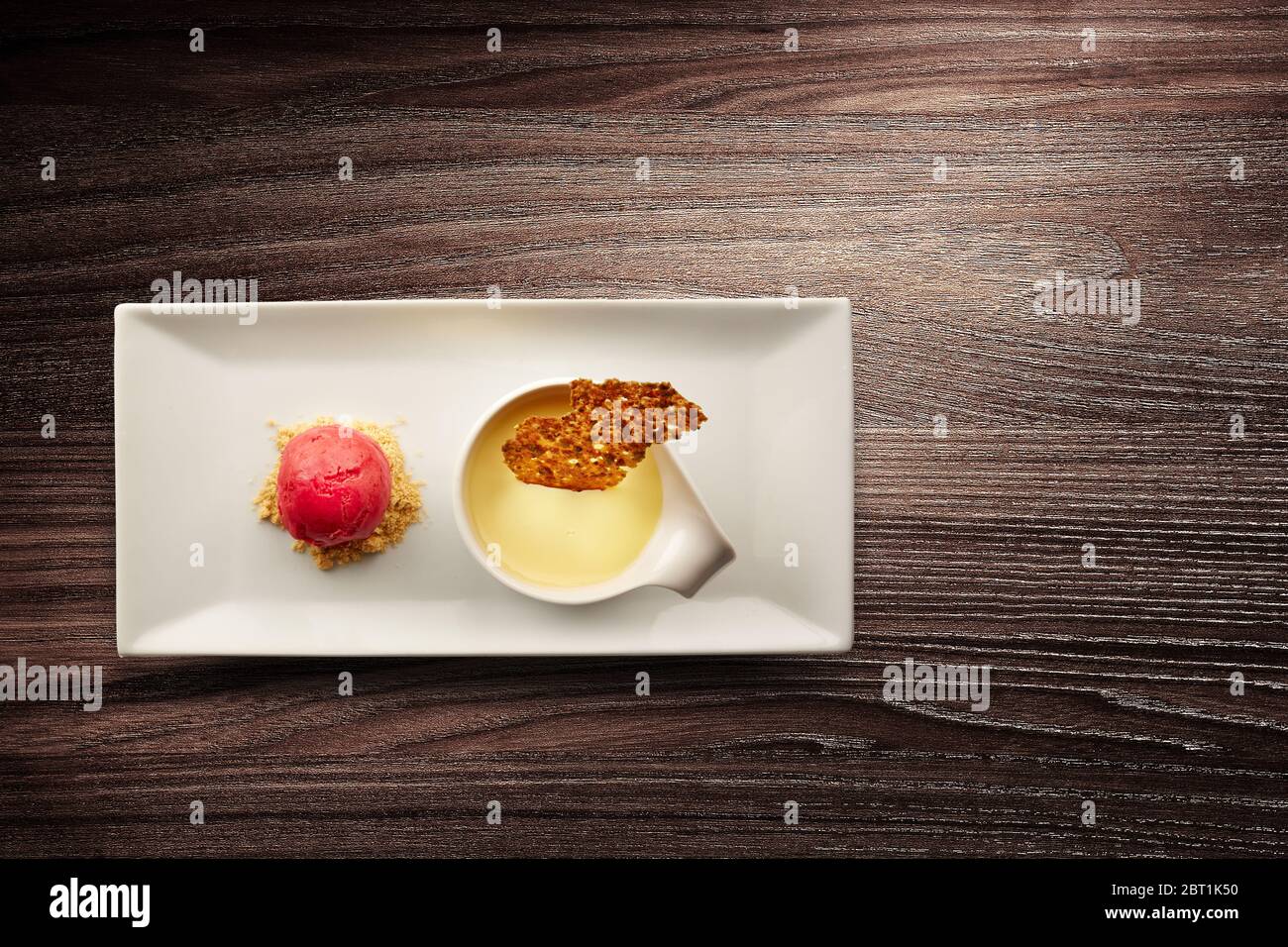 Directly above shot of a stylish nouvelle cuisine plate of creme brulee on wooden background Stock Photo