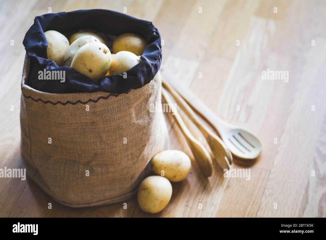 Raw potato food. Fresh potatoes in an old sack on wooden background. Top view Stock Photo