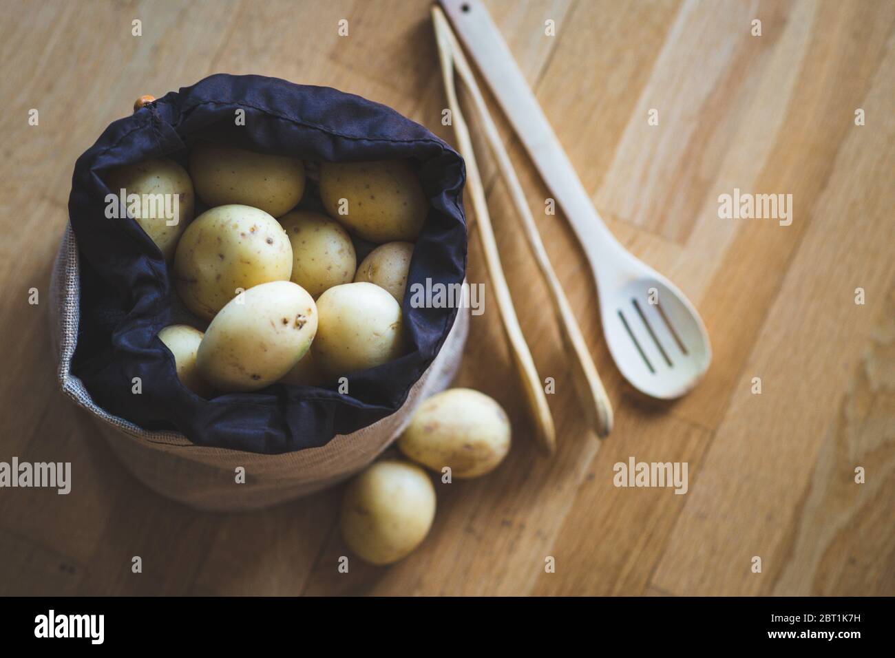 Raw potato food. Fresh potatoes in an old sack on wooden background. Top view Stock Photo