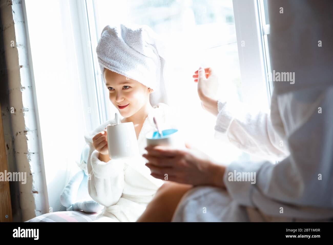 Mother and daughter, sisters have quite, beauty and fun day together at home. Comfort and togetherness. Concept of childhood, happiness, family's weekend, friendship, pajamas party. Domestic lifestyle. Stock Photo