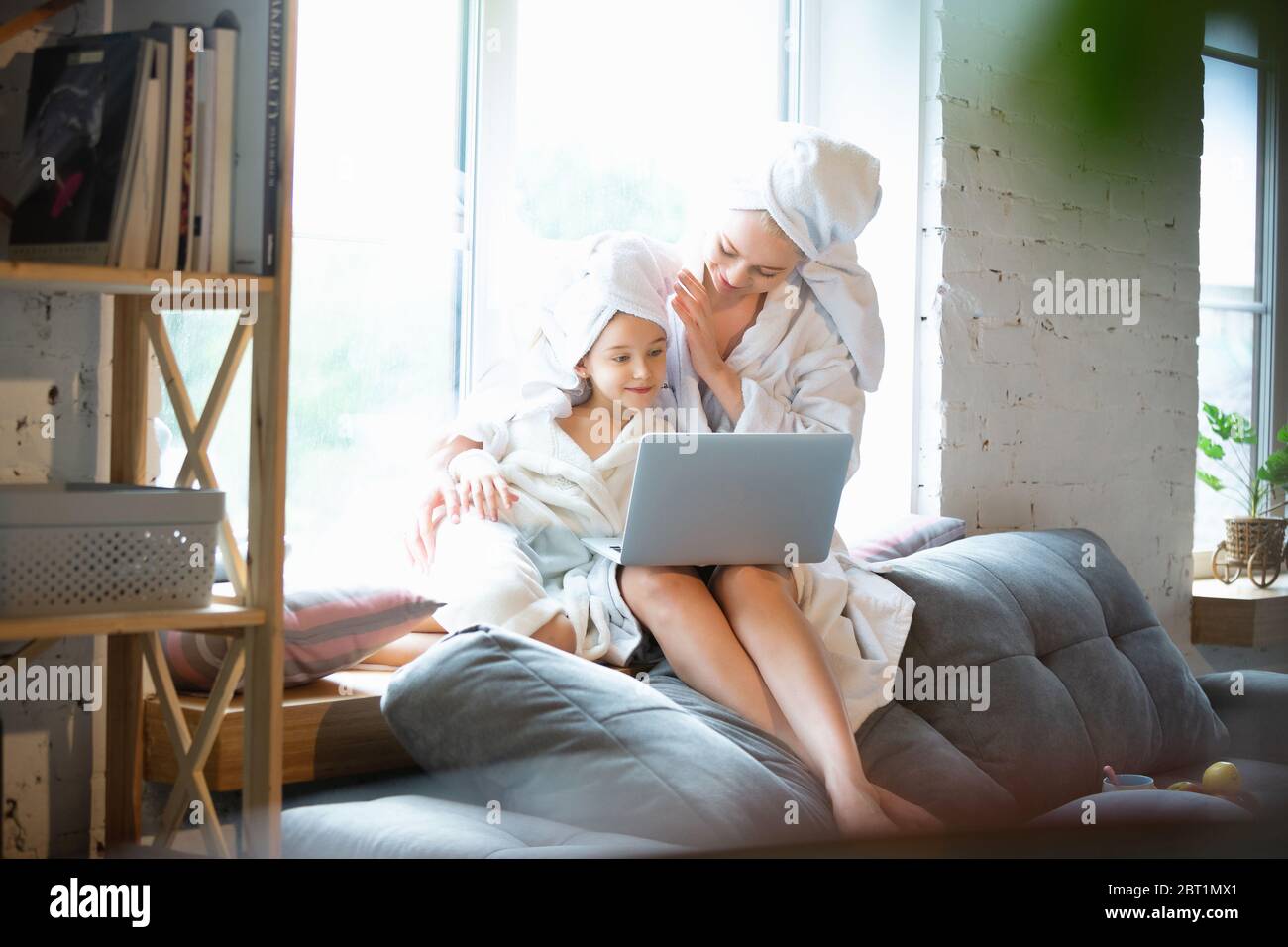 Mother and daughter, sisters have quite, beauty and fun day together at home. Comfort and togetherness. Concept of childhood, happiness, family's weekend, friendship, pajamas party. Domestic lifestyle. Stock Photo