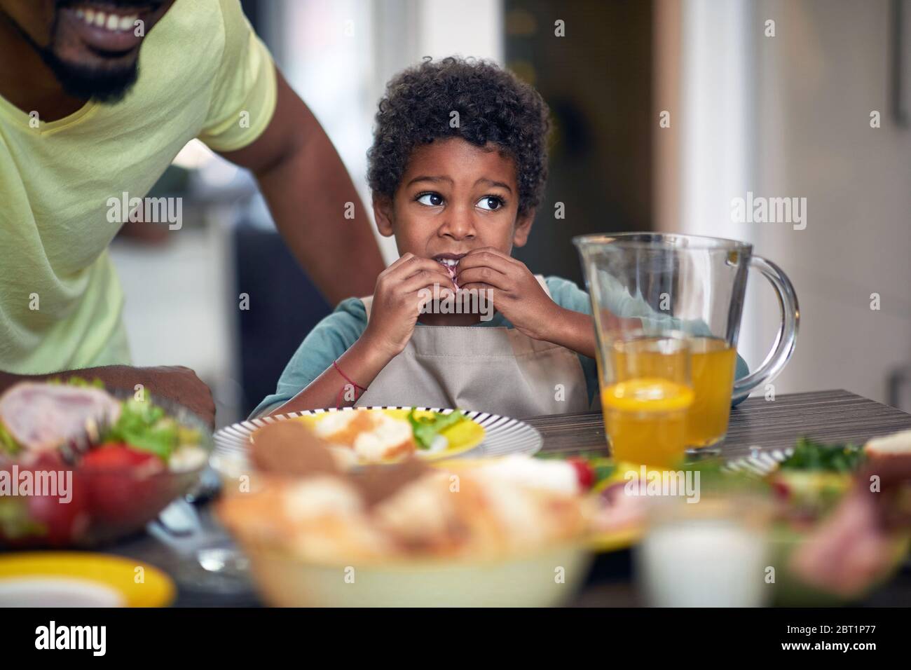 Little boy having breakfast. Afro American family at morning. Stock Photo