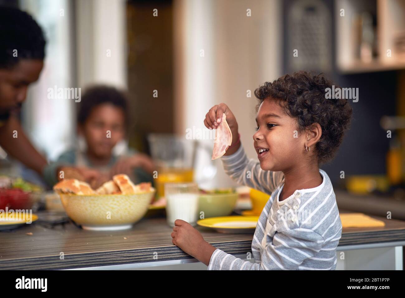 Little girl having breakfast. Afro American family at morning. Stock Photo