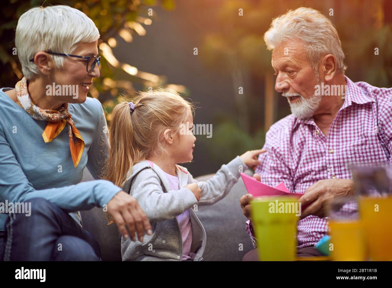 Happy funny family.Grandparents playing  with  smiling granddaughter. Stock Photo