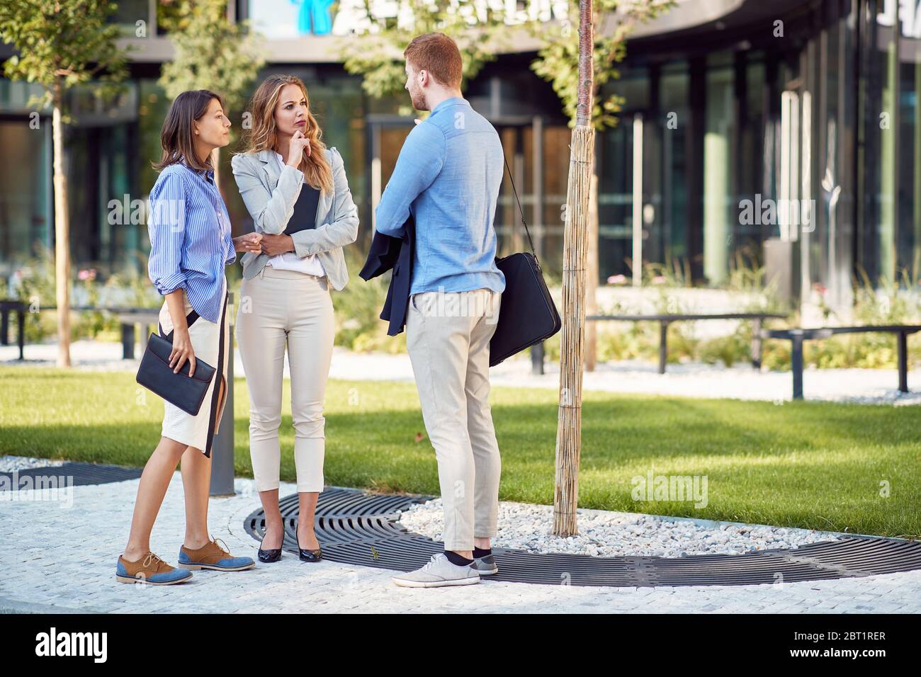group of young business people talking in front of a building. two female and one male colleague Stock Photo