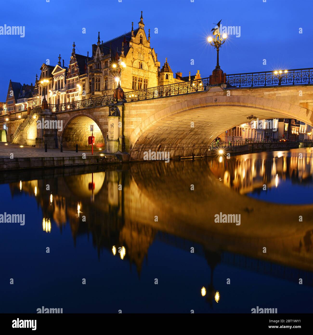 Cityscape of Gent at night by the Leie river with a bridge reflection, East Flanders, Belgium. Stock Photo