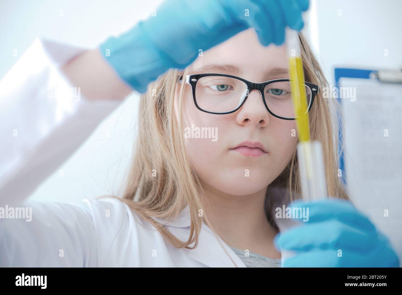 School Age Girl In Chemistry Class Using Test Tube And Pipette Wearing Protective Glasses Lab Coat And Gloves. Stock Photo