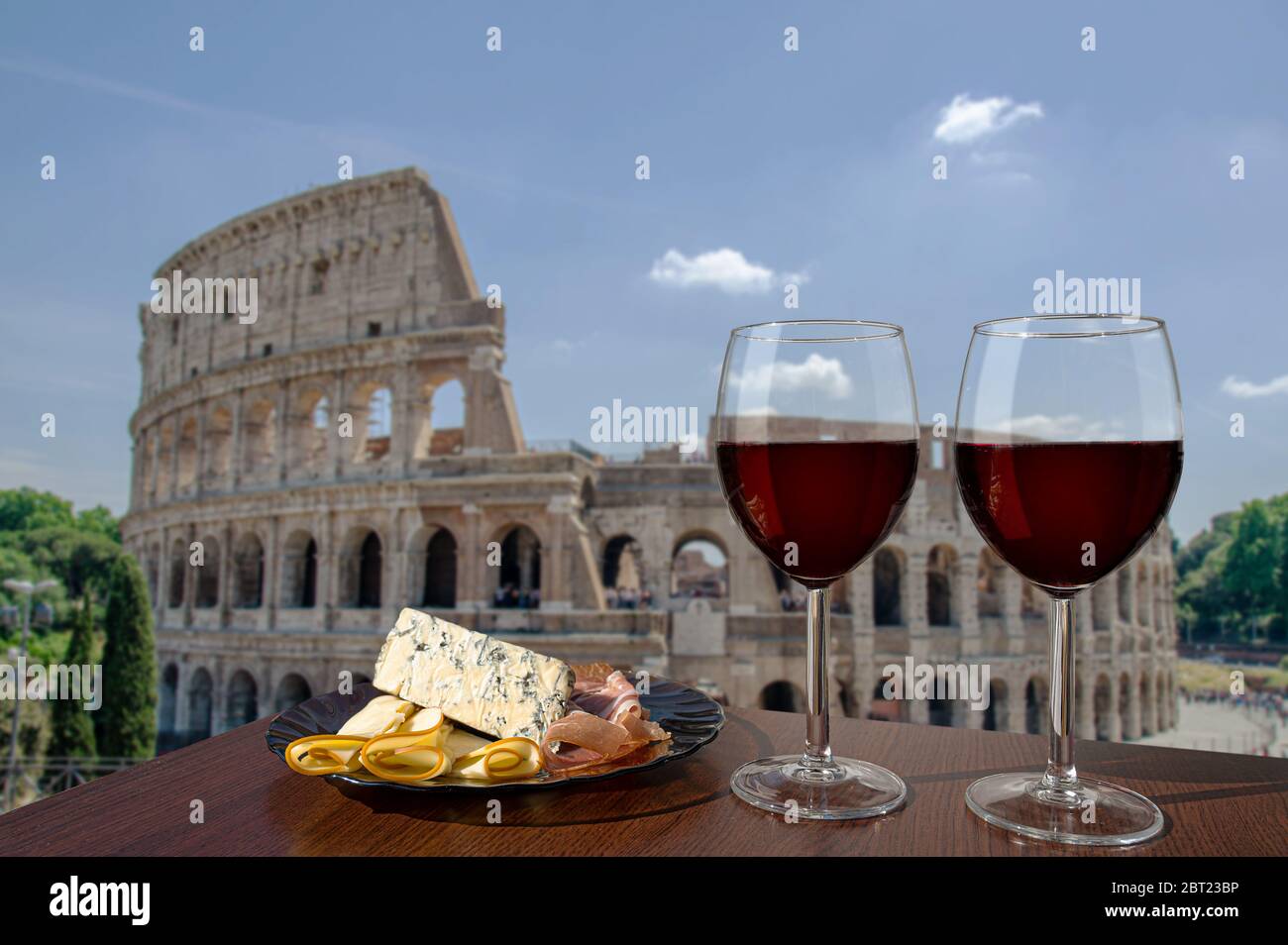 Two glasses of wine with charcuterie assortment on view of Colosseum (Coliseum) in Rome, Italy. Glass of red wine with different snacks - cheese plate Stock Photo
