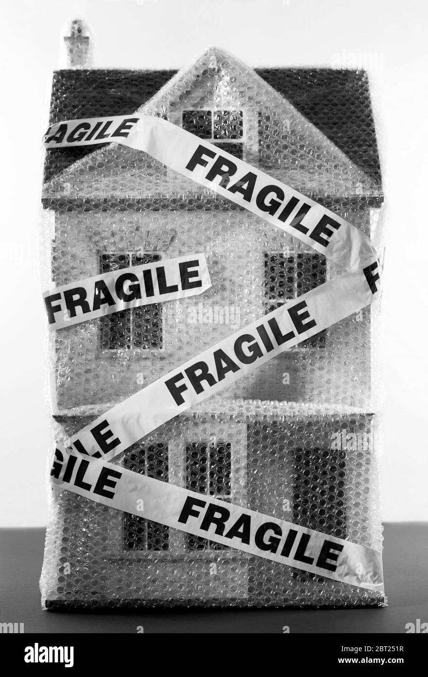Black and white photo of toy house wrapped in bubble wrap and fragile sticker concept Stock Photo