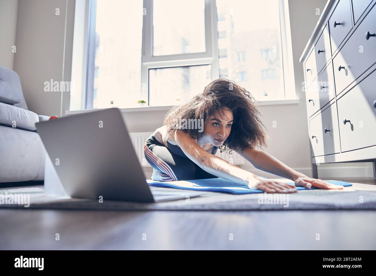 Concentrated international girl stretching her back at home Stock Photo ...
